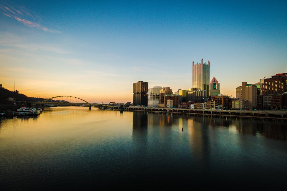 Beautiful sunset over the city skyline with reflections in the river, showcasing modern architecture and tranquil scenery.